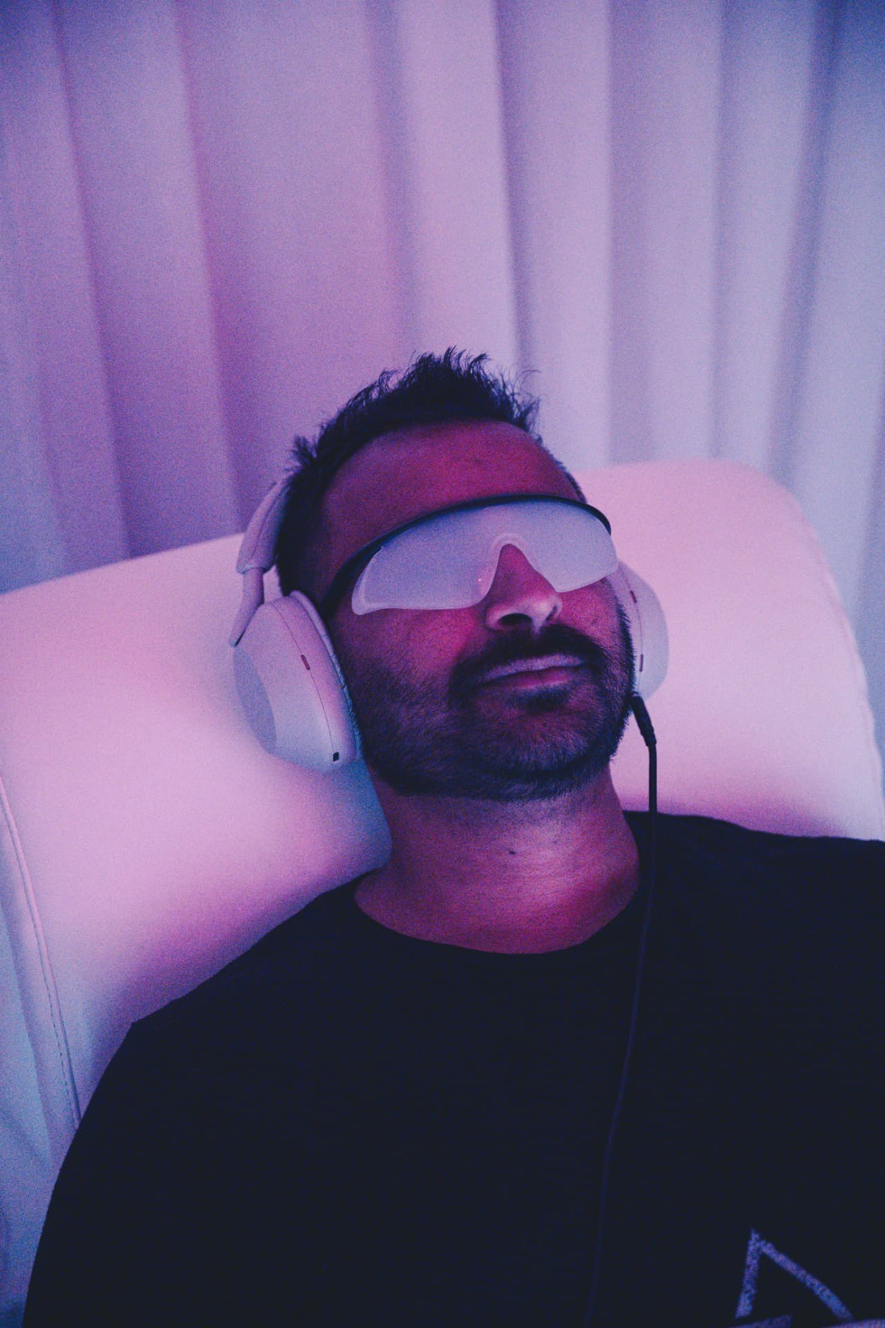 Athlete resting in the RE:SET lounger wearing light glasses and headphones